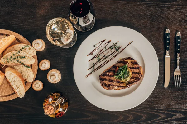 Vista dall'alto di bistecca di manzo, baguette e vino in tavola — Foto stock