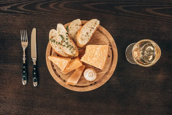 Top view of parmesan cheese with baguette slices on wooden board — Stock Photo