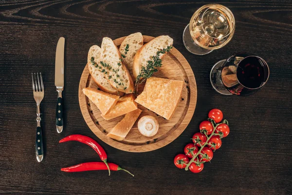 Vista superior del queso parmesano con rodajas de baguette y tomates cherry en la mesa - foto de stock