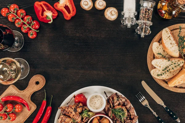 Blick von oben auf frisches Gemüse, gekochte Rindersteaks und Wein auf dem Tisch — Stockfoto