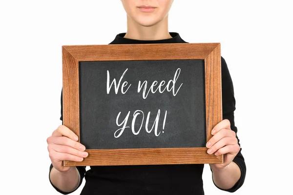 Cropped image of woman holding board with lettering we need you isolated on white — Stock Photo