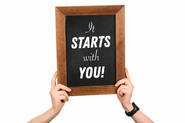 Cropped image of woman hands holding board with lettering it starts with you isolated on white — Stock Photo