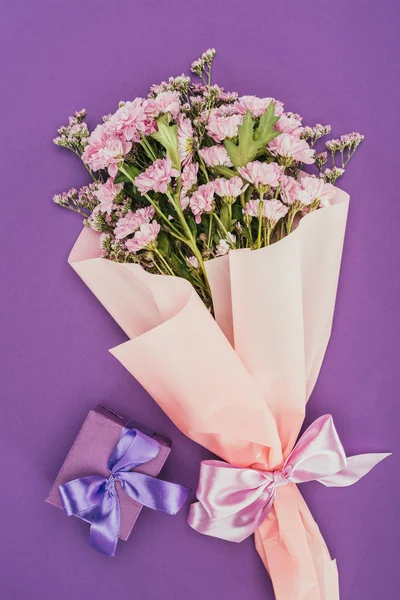 Букет красивых розовых цветов и подарочная коробка на фиолетовый — стоковое фото