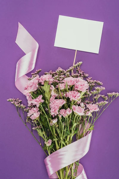 Bouquet di bellissimi fiori rosa con nastro e carta bianca su viola — Foto stock