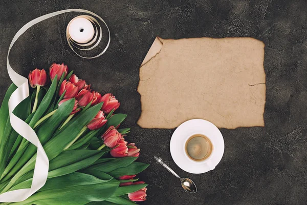 Vue de dessus de belles tulipes rouges, ruban, tasse de café et parchemin vierge — Photo de stock