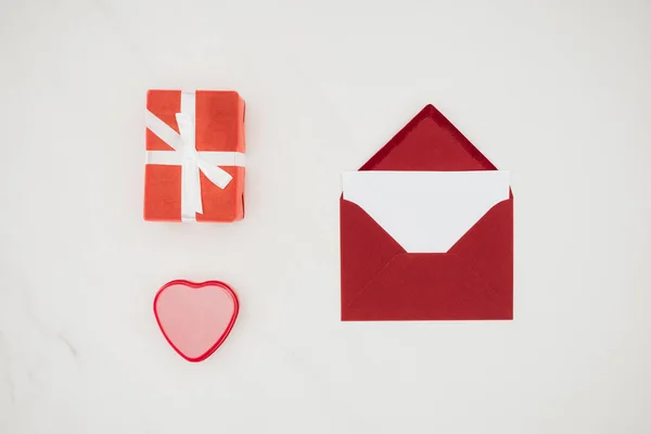 Vista superior del sobre rojo con papel en blanco y cajas de regalo aisladas en blanco - foto de stock