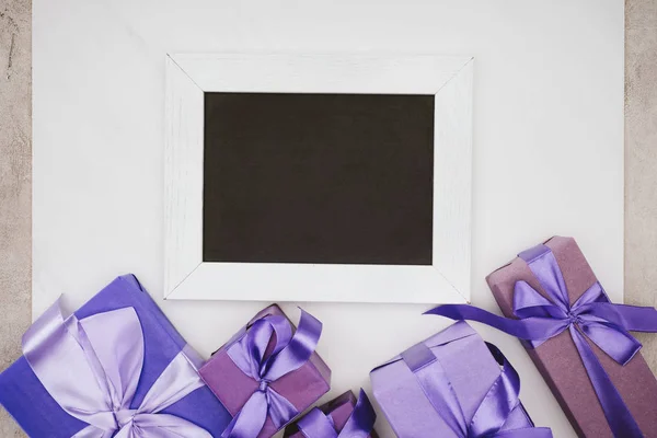 Top view of blank chalkboard with various gift boxes on white — Stock Photo