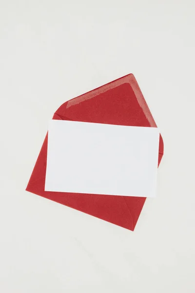 Vue du dessus de l'enveloppe rouge avec papier blanc isolé sur blanc — Photo de stock