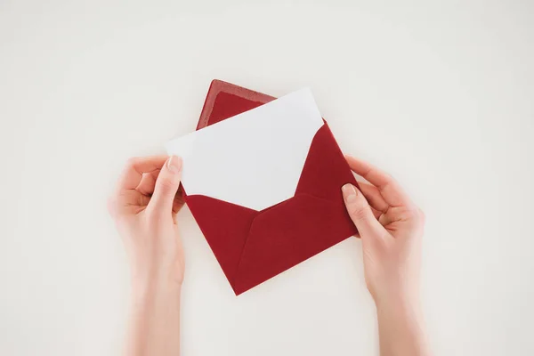 Plan recadré d'une femme ouvrant une enveloppe rouge avec du papier blanc isolé sur blanc — Photo de stock