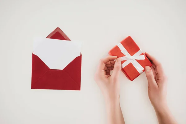 Обрізаний знімок жінки, що відкриває подарункову коробку з червоним конвертом ізольовано на білому — стокове фото