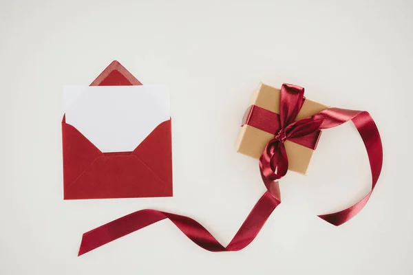 Вид зверху на червоний конверт з чистим папером і подарунковою коробкою ізольовано на білому — стокове фото