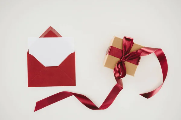 Top view of red envelope with blank paper and gift box isolated on white — Stock Photo