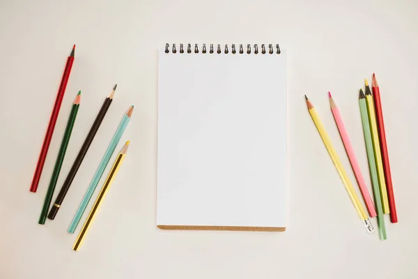 Vue du dessus du bloc-notes vierge avec crayons colorés isolés sur blanc — Photo de stock