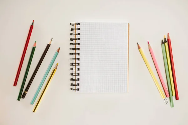 Vista dall'alto di notebook bianco con matite colorate isolate su bianco — Foto stock
