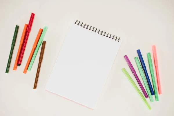 Vista superior do bloco de notas em branco com marcadores coloridos isolados no branco — Fotografia de Stock