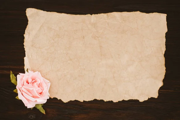 Top view of blank aged paper and rose flower on wooden table — Stock Photo