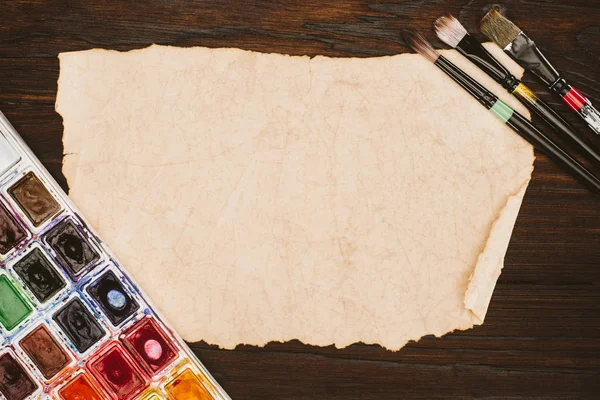Top view of blank aged paper and painting supplies on wooden table — Stock Photo