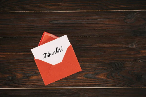 Vista superior do envelope vermelho com letras de agradecimento em papel na mesa de madeira — Fotografia de Stock