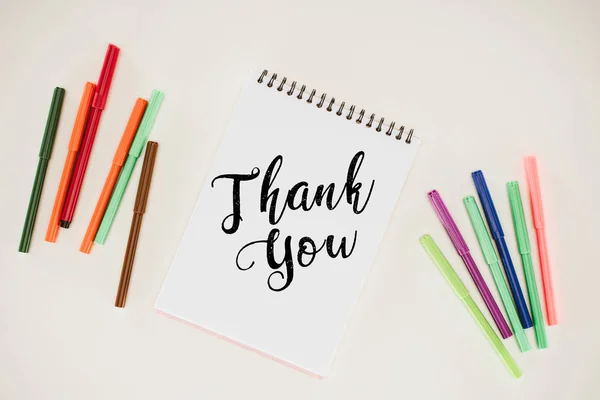 Top view of notepad with thank you lettering and colorful markers isolated on white — Stock Photo