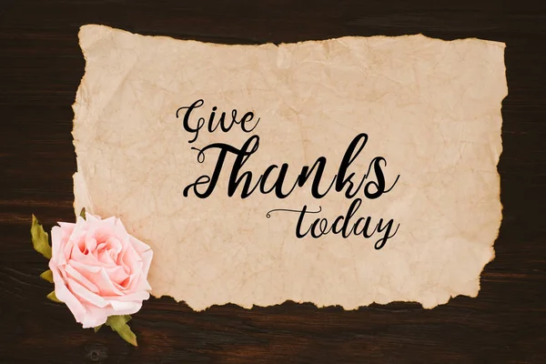 Ansicht von gealtertem Papier mit Danksagung heute Schriftzug und Rosenblume auf Holztisch — Stockfoto