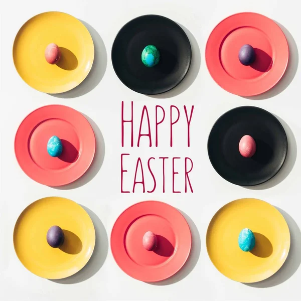 Рамка великодніх яєць на барвистих тарілках з щасливим пасхальним написанням — стокове фото