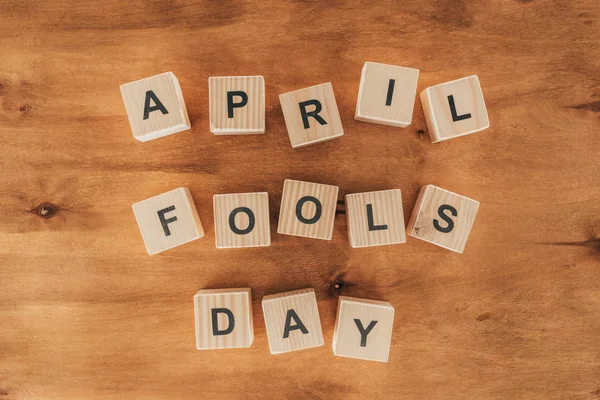 Top view of arranged wooden cubes in april fools day lettering on wooden tabletop, 1 april holiday concept — Stock Photo