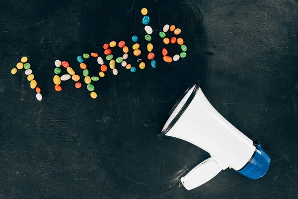 Tendido plano con altavoz y caramelos dispuestos en 1 letras de delantales en la mesa negra - foto de stock