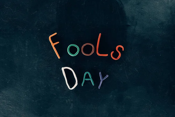 Top view of fools day lettering made of plasticine on black surface — Stock Photo