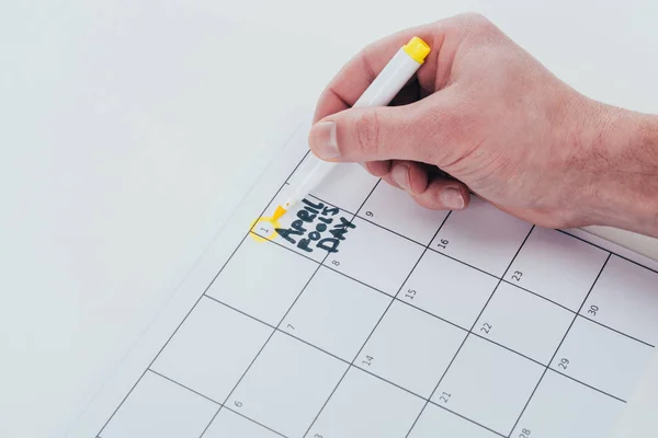 Visión parcial del hombre tomando nota en el calendario aislado en gris, abril tontos concepto de día - foto de stock