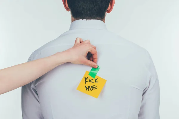 Cropped shot of woman putting note with kick me lettering on males back, 1 april holiday concept — Stock Photo