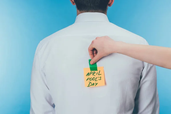 Cropped shot of woman putting note with april fools day lettering on males back, april fools day concept — Stock Photo