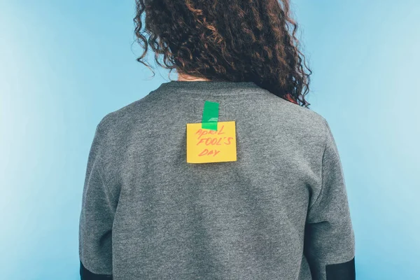 Rückseite Frau mit Zettel auf Klebeband mit rückseitigem Aprilscherz-Schriftzug, Aprilscherz-Konzept — Stockfoto