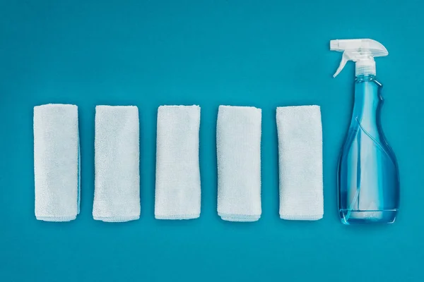 Top view of row of rags and spray bottle isolated on blue — Stock Photo