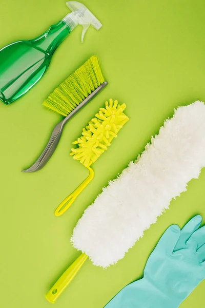 Вид сверху на различные чистящие щетки и резиновые перчатки, изолированные на светло-зеленом — стоковое фото