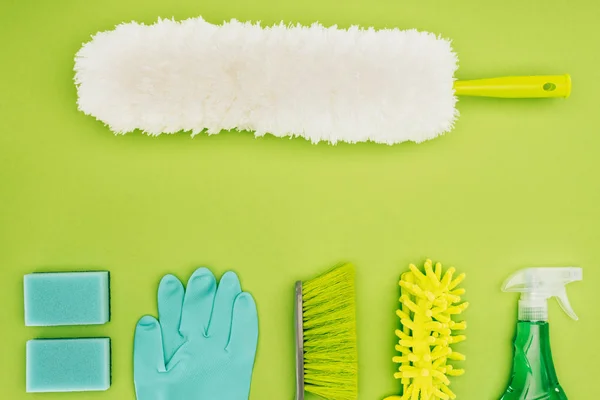 Vista superior del cepillo de polvo y artículos de limpieza aislados en verde claro - foto de stock
