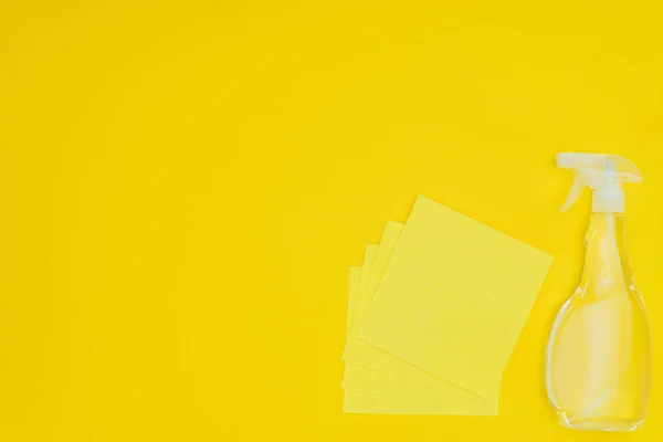 Підвищений вид на жовті ганчірки і пляшку розпилення ізольовані на жовтому — стокове фото