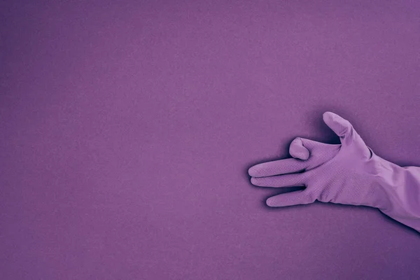 Imagen recortada de mujer mostrando signo con la mano en guante protector de goma aislado en violeta - foto de stock