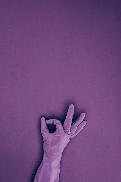 Imagen recortada de la mujer que muestra signo ok en guante protector de goma aislado en violeta - foto de stock