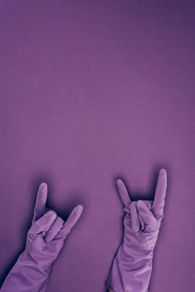 Cropped image of woman showing rock signs in rubber protective gloves isolated on violet — Stock Photo