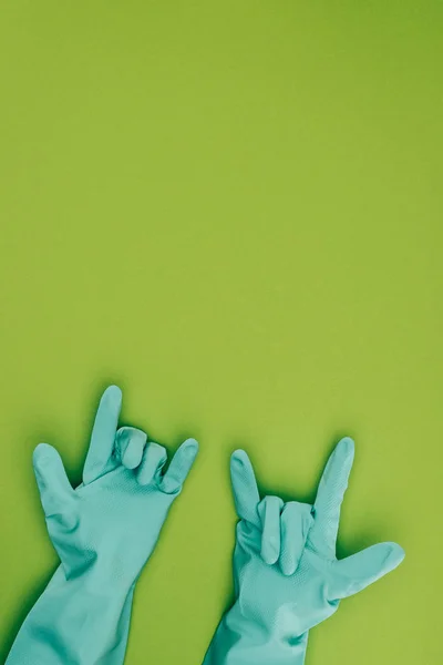 Immagine ritagliata di donna che mostra segni di roccia in gomma guanti protettivi isolati su verde — Foto stock