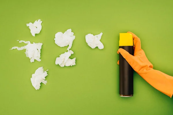 Imagem cortada de mulher segurando frasco de spray perto de pedaços de guardanapos amassados isolados em verde — Fotografia de Stock