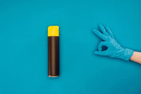 Imagen recortada de la mujer que muestra signo ok cerca de botella de aerosol aislado en azul - foto de stock