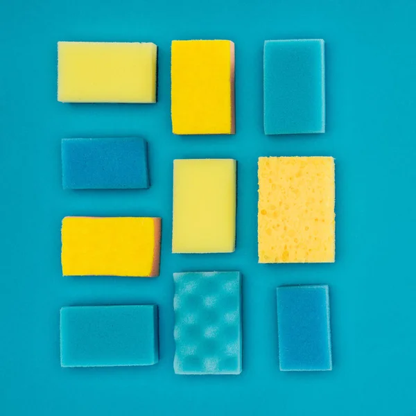 Vista superior de esponjas de lavagem amarelas e azuis isoladas em azul — Fotografia de Stock