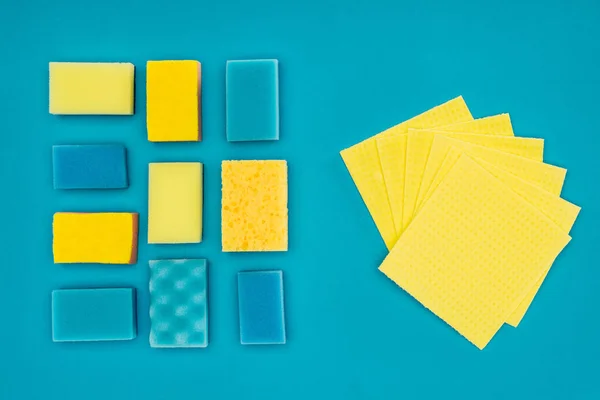 Top view of yellow and blue washing sponges and rags isolated on blue — Stock Photo