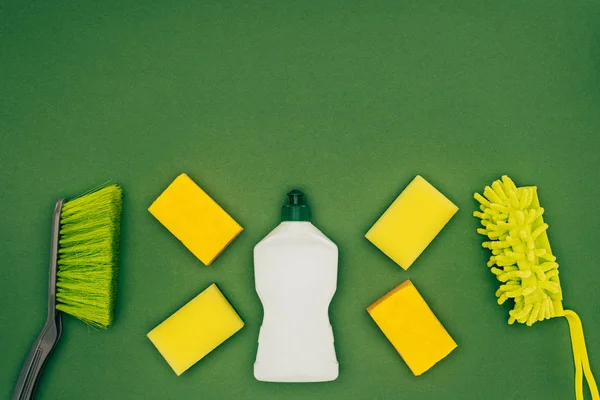 Top view of washing sponges, cleaning fluid and brushes isolated on green — Stock Photo