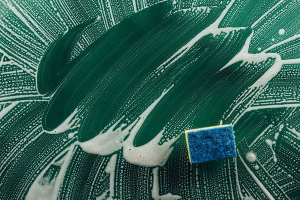 Elevated view of washing sponge and foam on dirty surface — Stock Photo