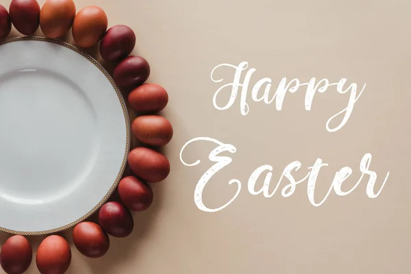 Top view of painted easter eggs around plate with Happy Easter inscription — Stock Photo