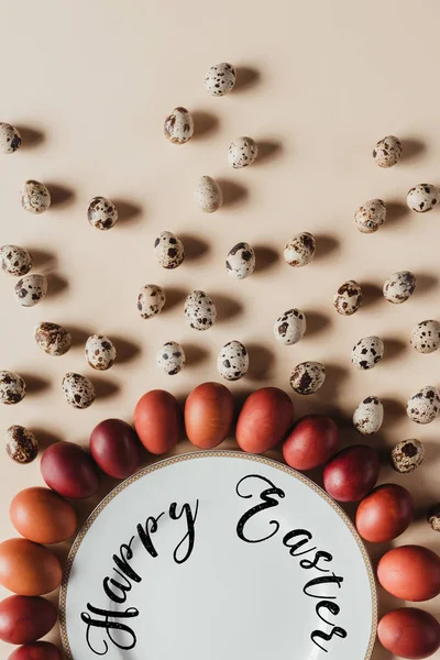 Essenszusammensetzung mit Wachteln und Hühner-Ostereiern um Teller mit fröhlicher Osterbeschriftung — Stockfoto