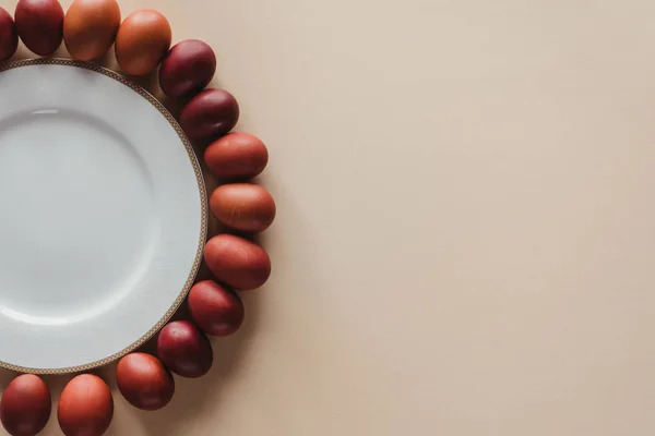 Top view of chicken easter eggs around plate on beige with copy space — Stock Photo