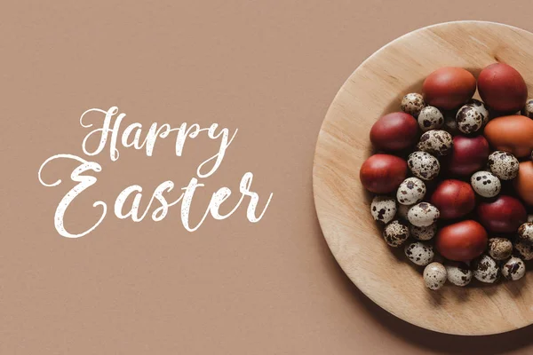 Vista superior de huevos de pascua de pollo y codorniz en plato de madera con letras de feliz Pascua - foto de stock